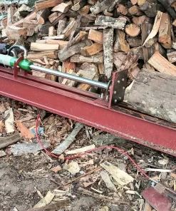 Máy bổ củi thủy lực nằm ngang cạnh bãi củi, với khúc gỗ lớn trên thân máy