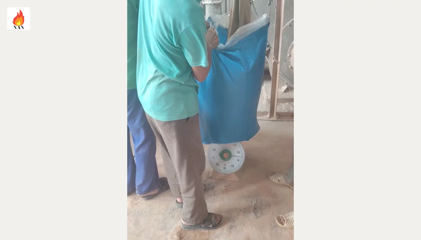Bao vật liệu màu xanh đặt trên cân bàn kim trong quá trình đóng bao cao lanh.